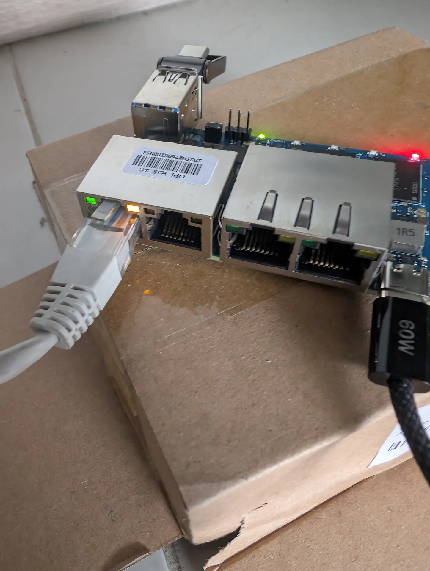 Phase 2: Orange Pi R2S flashing eMMC — red LED, green board LED, and two Ethernet LEDs (green + amber) visible
